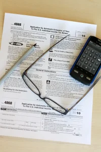 Tax return form on a desk with a pen, glasses and a phone