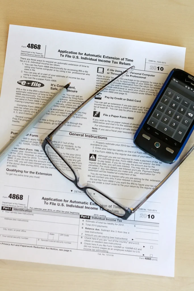 Tax return form on a desk with a pen, glasses and a phone